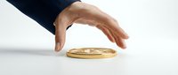 Male hand in dark blue sleeve protecting golden coin on white surface, symbolizing financial security, investment protection, and wealth management.
