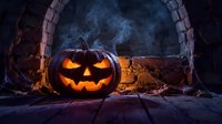 Glowing jack-o-lantern with menacing expression sits in dark stone archway surrounded by autumn leaves and fog for seasonal holiday celebrations.