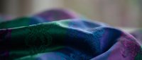 Vibrant iridescent fabric with holographic rainbow colors creating flowing waves and ripples. Futuristic textile material for fashion and design projects.