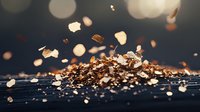 Crushed gold leaf and metallic particles scatter across dark surface with bokeh lights, suitable for luxury branding, cosmetics packaging, and premium product photography.