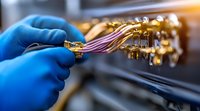 Laboratory technician in blue protective gloves connecting gold-plated electronic components and wires during precision testing or research procedure in modern facility.