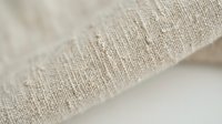 Natural linen fabric texture with loose weave showing organic cotton fibers and textile detail for sustainable fashion and home decor projects.
