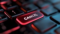 Red illuminated cancel button on black computer keyboard with dramatic lighting, close-up view showing modern technology interface for business and gaming.