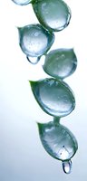 Crystalline water drops falling in leaf-shaped formation against white background, creating serene natural pattern with green tints and reflections.
