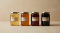 Four glass jars of different honey varieties with handwritten labels arranged in row on neutral background for organic food marketing and packaging design.