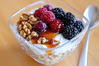 Healthy breakfast parfait with Greek yogurt, fresh berries, walnuts and honey in glass bowl on wooden table for nutritious morning meal.