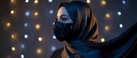 Middle Eastern woman wearing ornate black face mask and flowing hijab against bokeh lights background for fashion and cultural portrait photography.