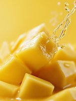Fresh mango cubes with water splash on yellow background, close-up view showing juicy tropical fruit texture and dynamic liquid motion in bright lighting.