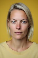 Close-up portrait of young Caucasian woman with blonde hair and blue eyes wearing yellow sweater against golden background, natural makeup and confident expression.