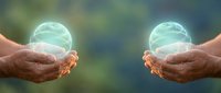 Two hands holding glowing green energy spheres with swirling patterns against blurred natural background for wellness and healing concepts.