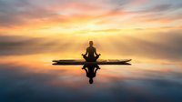 Silhouette of person meditating in lotus pose on wooden dock at serene lake during golden sunrise with perfect water reflections and peaceful atmosphere.