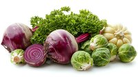 Fresh organic vegetables on white background - red beets with cross sections, brussels sprouts, garlic bulb and curly parsley arranged in rustic composition.