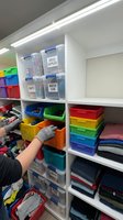 Organized storage shelving unit with colorful plastic bins and containers for home office supplies and classroom materials organization system.