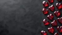 Red crystal hearts scattered on dark background, romantic love concept for Valentine's Day cards, wedding invitations and anniversary celebrations.