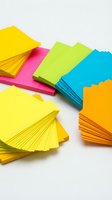 Colorful stacks of adhesive notes in yellow, pink, lime green, cyan, and orange arranged on white background for office and creative projects.