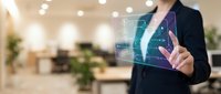 Businesswoman in dark blazer interacting with holographic digital interface displaying data analytics and financial charts in modern office environment for technology and business solutions.