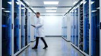 IT technician walking through modern data center server room with blue LED lighting and white equipment racks for cloud computing infrastructure.