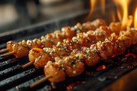 Grilled shrimp skewers with herbs and spices cooking on flaming barbecue grill, close-up view showing juicy texture and char marks in warm lighting.
