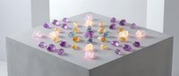 Colorful gemstones scattered on white surface with glowing light effects creating magical sparkle for jewelry design and luxury concepts.