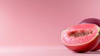 Fresh ripe guava fruit cut in half showing pink flesh and seeds on pink background, minimal food photography composition for healthy eating concept.