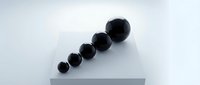 Black spheres arranged in ascending size order on white surface creating minimalist geometric composition for modern design projects.