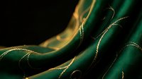 Luxurious emerald green silk fabric with golden threads flowing in elegant waves against dark background for premium textile and fashion design projects.