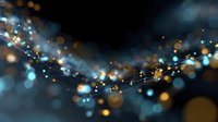 Magical glowing particles with blue and golden bokeh lights floating in dark space creating ethereal abstract background with dreamy atmosphere.
