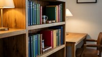 Cozy home office interior with wooden bookshelf filled with colorful books, warm lighting and comfortable workspace for reading and studying.