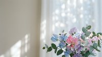 Delicate pastel flower bouquet with eucalyptus leaves in soft natural light creating gentle shadows on neutral wall background for home decor and lifestyle.