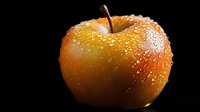 Fresh red apple with water droplets on black background for healthy eating and nutrition concepts.