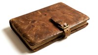 Vintage brown leather journal with worn patina and buckle closure on white background isolated for design projects and creative layouts.