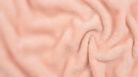 Soft pink fabric texture with flowing folds and gentle waves creating elegant drapery pattern for fashion design and textile backgrounds.