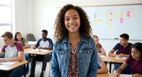 Young mixed-race female student smiling in modern classroom with diverse classmates studying at desks. Educational environment for learning and academic success.