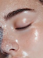 Close-up of wet glowing skin with water droplets and closed eye showing natural eyebrow and long eyelashes, highlighting hydrated skincare results.