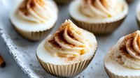 Freshly baked cupcakes with creamy frosting and cinnamon sugar topping arranged on a white plate for bakery, dessert, and food styling projects.
