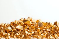 Shimmering gold nuggets and fragments scattered on white background, creating luxurious texture for jewelry or financial concepts.