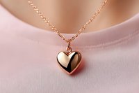 Rose gold heart pendant necklace on delicate chain against soft pink fabric background, showcasing elegant jewelry design for romantic occasions and fashion accessories.