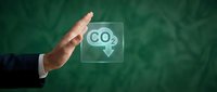 Business hand stopping CO2 emissions with protective gesture against green background for environmental protection and carbon footprint reduction concepts.