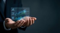 Young male professional in business suit holding glowing digital financial charts and stock market graphs in palm of hand against dark background for investment and trading concepts.