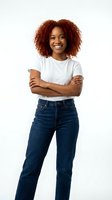 Confident young African American woman with curly red hair smiling with arms crossed wearing white t-shirt and jeans isolated on white background.