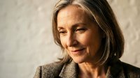Mature woman with shoulder-length brown hair and fair complexion wearing brown blazer, smiling warmly against neutral background. Suitable for business, corporate, and professional lifestyle content.