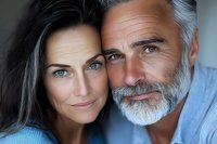 Mature couple embracing intimately, showing love and connection in middle age relationship, gray-haired man with beard and brunette woman smiling warmly.