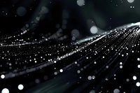 Abstract glowing particles and light trails creating dynamic movement against dark background, bokeh effect adds depth and atmosphere. Suitable for tech concepts.