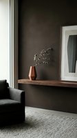 Minimalist interior with dark charcoal wall, wooden shelf displaying terracotta vase and dried botanical stems, black armchair, and white-framed mirror for modern home decor and design inspiration.