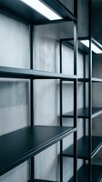 Empty black metal shelving unit against concrete wall, industrial loft interior with modern minimalist design and dramatic lighting.