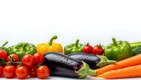 Fresh organic vegetables including eggplant, bell peppers, tomatoes, carrots and herbs arranged on white background for healthy cooking and nutrition.