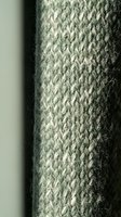 Close-up of sage green knitted wool fabric showing detailed cable stitch pattern texture for cozy winter fashion and textile design projects.