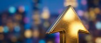 Golden arrow pointing upward against blurred bokeh background with blue and warm lights, symbolizing growth, success, progress and positive business direction for corporate designs.