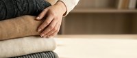 Man in cozy sweater relaxing at home with hands folded on soft cushion creating peaceful domestic atmosphere for wellness and comfort concepts.
