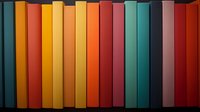 Colorful book spines arranged in rainbow spectrum order on shelf, showing vibrant gradient from yellow through orange, red, and turquoise tones. Perfect for education themes.